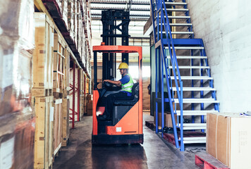 Asian senior man driving forklift truck delivery box to cargo shipping in distribution warehouse. Export import or logistics service business. employee people working in factory industrial concept © winnievinzence