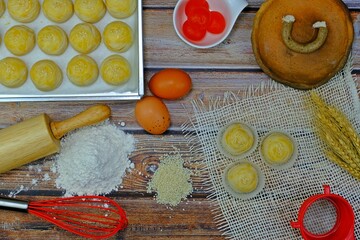 Delicious homemade Chinese pastries (mini moon cakes or bings) with mung bean and preserved egg yolk surrounded by key ingredients.