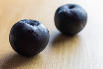 A Two plums on natural wood, natural vegan food. Concept of eating fruit and digestive food to go to the toilet.