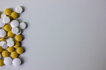A lot of white and yellow pills and capsules on a white background
