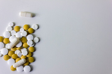 A lot of white and yellow pills and capsules on a white background