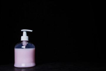 Pink liquid soap on a black background. Cleaning agent. Right empty space for inscription