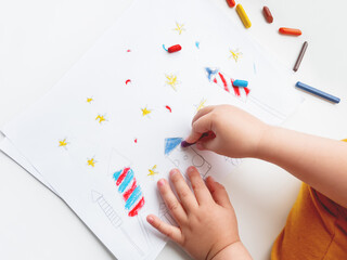 Toddler sits on windowsill and draws colorful fireworks. Child's picture to 4th of July celebration. Independence Day of USA symbol.