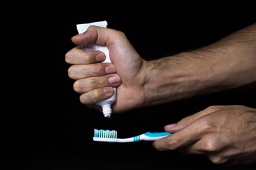A male hand squeezes a toothpaste onto a toothbrush. Oral hygiene. Teeth cleaning