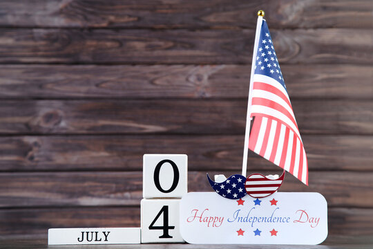 Text Happy Independence Day with cube calendar and flag on wooden background
