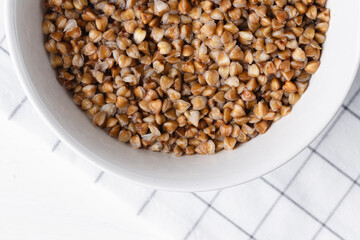 Cooked buckwheat in white bowl close up