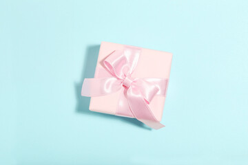 Gift box with ribbon bow on blue background. Minimalism concept