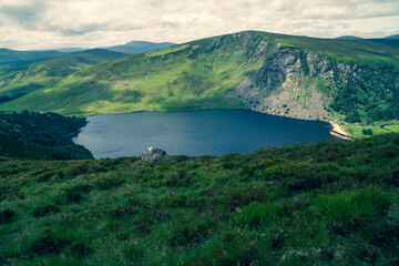 Naklejka na ściany i meble Panoramic view of The Guinness Lake (Lough Tay) - a movie and series location, such as Vikings. Close to Dublin City, popular tourist destination. Warm colors, vintage look