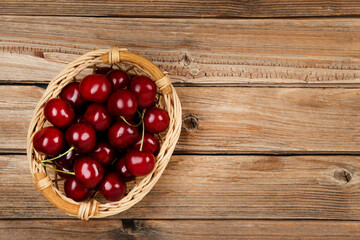 Sweet cherries in basket on brown wooden table