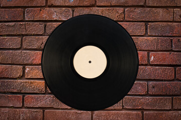 A black gramophone record against a brick wall
