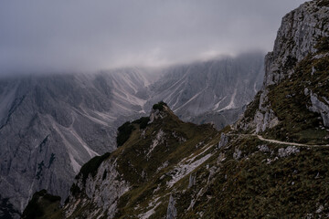 Fototapeta premium Dolomites Alps. Cadini di Misurina. Italy. Group of travellers stays on the top of the mountain in heavy fog over a cliff wrapped by white clouds