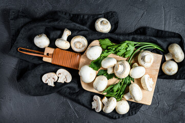 Obraz na płótnie Canvas fresh mushrooms champignon on a wooden cutting Board. Black background. Top view