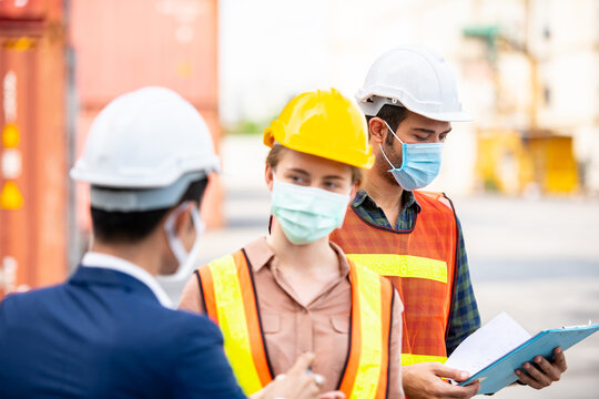 Industrial worker wear hygienic mask  and infrared thermometer at logistic warehouse container workplace,during quarantine and social distancing covid-19 pandemic illness.