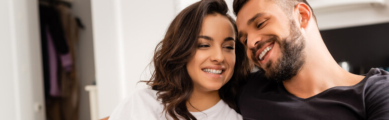 panoramic crop of cheerful couple smiling at home