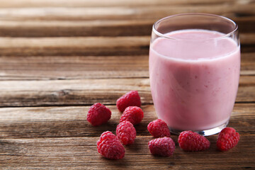 Raspberry smoothie in glass on brown wooden table