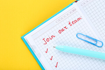 Text Join Our Team in notepad with pen and clip on yellow background