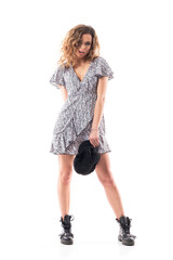 Fototapeta premium Sexy young woman in dotted dress with untied boots holding cap looking at camera. Full length portrait isolated on white background. 