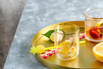Set from homemade refreshing cold lemonade from berries and lemon fruits in a glasses with plastic straws on a round tray.