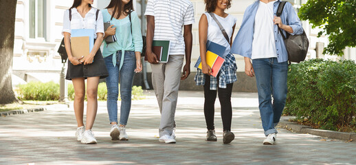 Cheerful teen students leaving college after classes, walking together outddors