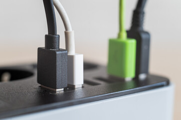 Modern convenient multi-port usb charger for devices. Close-up of multi-colored cables in a power outlet. Macro. pluged in.