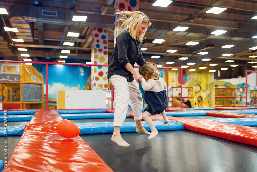 Wall mural mother and little girl jumping on a trampoline