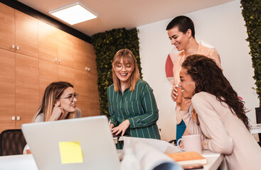 Group of modern young business women in casual wear discussing architectural designs in the creative office.