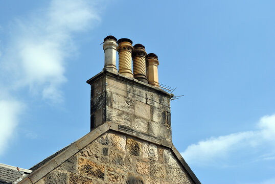 Gable of Old Stone Building with Chimneys against Blue Sky 