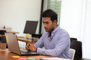 Portrait of Young business indian man working with laptop at office