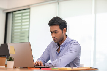 Fototapeta premium Portrait of Young business indian man working with laptop at office
