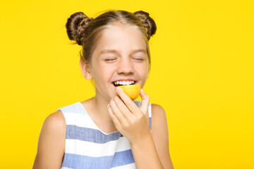 Young girl eating lemon fruit on yellow background