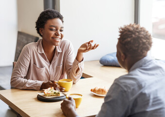 Joyful black couple having fun on first date at modern coffee shop