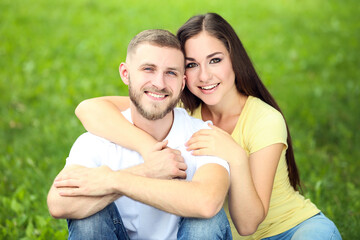 Happy young couple sitting on the grass in the park