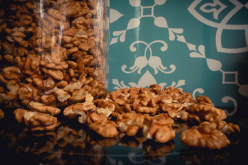 Closeup of big shelled walnuts pile. Closeup of man cracking walnuts with nutcracker in the hand.