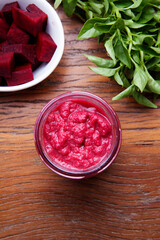 Nutrition concept - Healthy meals in glass jars over wooden background. Canned homemade beetroot in glass jar with fresh organic beetroots and rosemary plant.