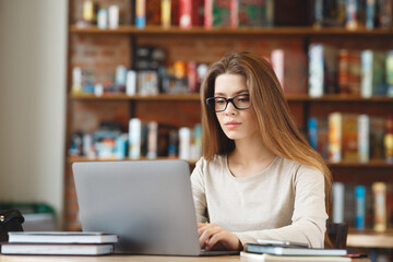 Young girl writing blog, chatting online, working on laptop