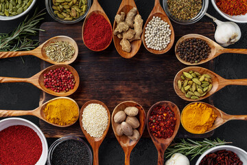 Vivid colorful spices in wooden spoons on wooden background