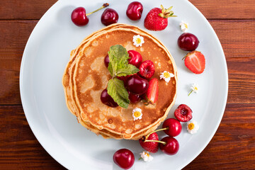 Breakfast. Pancakes with berries on a wooden background. Сopy space, top view