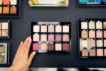 Woman with brush choosing shadows, cosmetics store