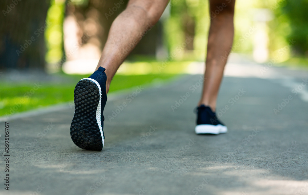 Wall mural closeup view of young black runner on jogging track at park