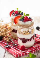 Tasty yoghurts with muesli, fresh berries and jam on wooden table. Healthy breakfast.