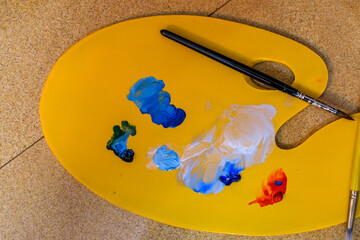 Oil painting palette full of colors and brushes kept on floor