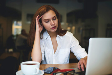 Young attractive female student  surfing internet and chatting with friends in social networks recreating after hard day in college with cup of coffee using technologies and 5G wireless connection