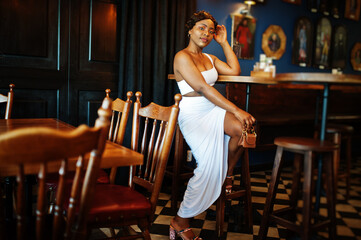 African american woman, retro hairstyle in white dress at restaurant.