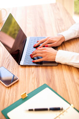 Close-up shot of businesswoman's hands while typing on laptop