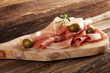 Italian prosciutto crudo or jamon with rosemary. Raw ham appetizer on table
