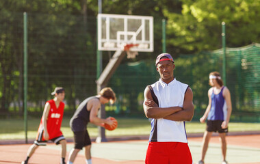 Serious African American basketball player and his multiracial team at outdoor court, blank space © Prostock-studio
