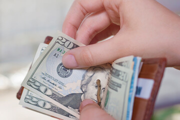 Hands hold a wallet with different bills on a blurred background. The concept of profit, salary, rent, inflation, prosperity, price growth.