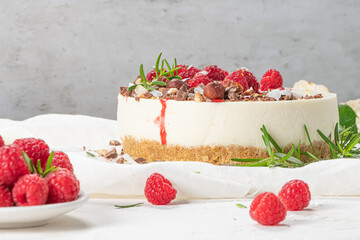 Cheesecake with raspberries, chocolate, hazelnuts and rosemary leaves on kitchen coutertop