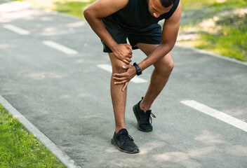 African American jogger suffering from pain in knee during his morning run at park