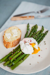 green asparagus with egg benedict with pepper and baguet with butter